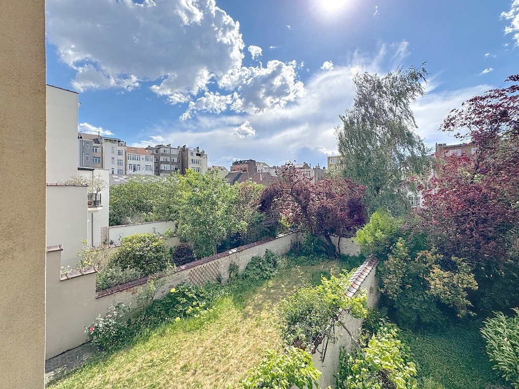 Jardin urbain paisible avec nature luxuriant et bâtiments modernes sous un ciel bleu.