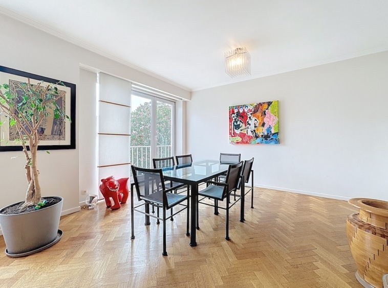 Salle à manger contemporaine avec table en verre, art coloré et sculptures rouges élégantes