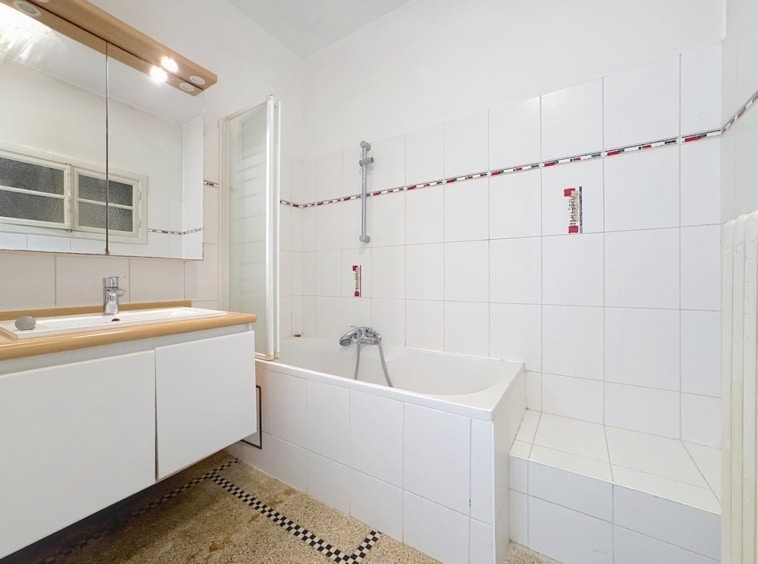 Salle de bain moderne et élégante avec miroir, baignoire, touche de couleur et design épuré.