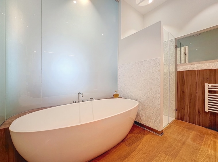 Salle de bain moderne avec baignoire îlot, douche en verre, ambiance élégante et apaisante.