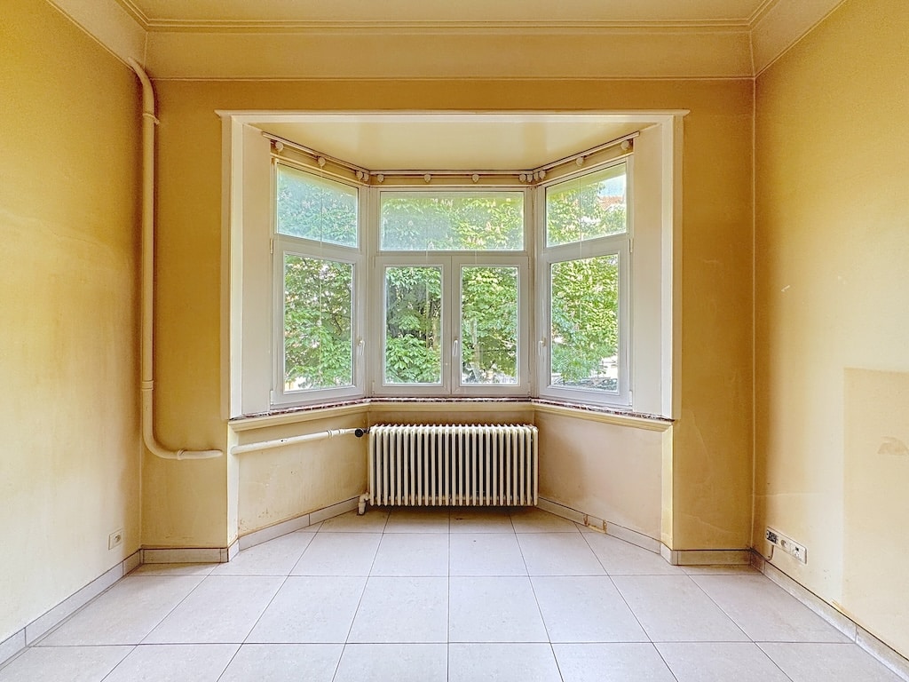 Salon lumineux avec grande baie vitrée offrant vue panoramique et intérieur accueillant et neutre.
