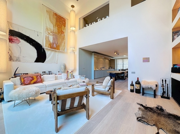 Salon moderne lumineux avec cuisine ouverte, œuvre colorée, canapé blanc et décoration élégante.