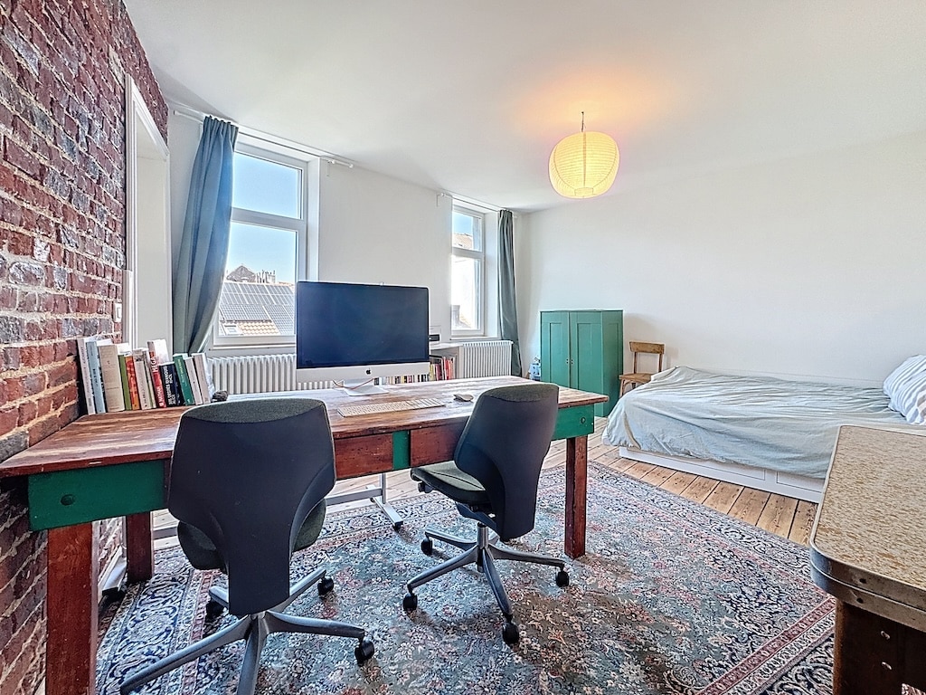 Espace de vie moderne avec bureau coloré, coin nuit cosy, mur en briques et lumière naturelle