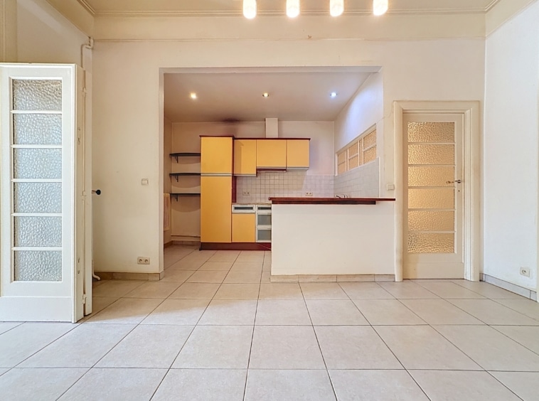Espace ouvert moderne avec cuisine jaune lumineuse, design minimaliste et grande luminosité naturelle.