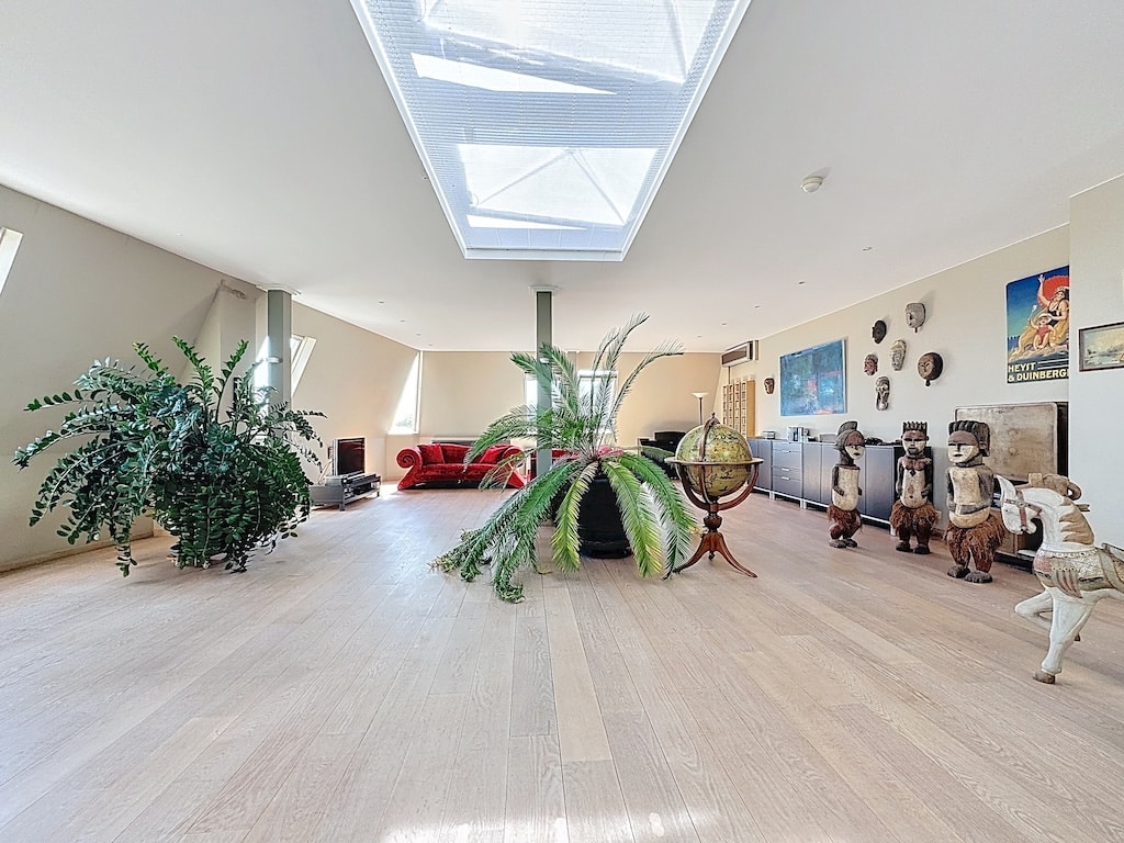 Salon lumineux avec mobilier coloré, plantes, œuvres d’art éclectiques et lumière naturelle.
