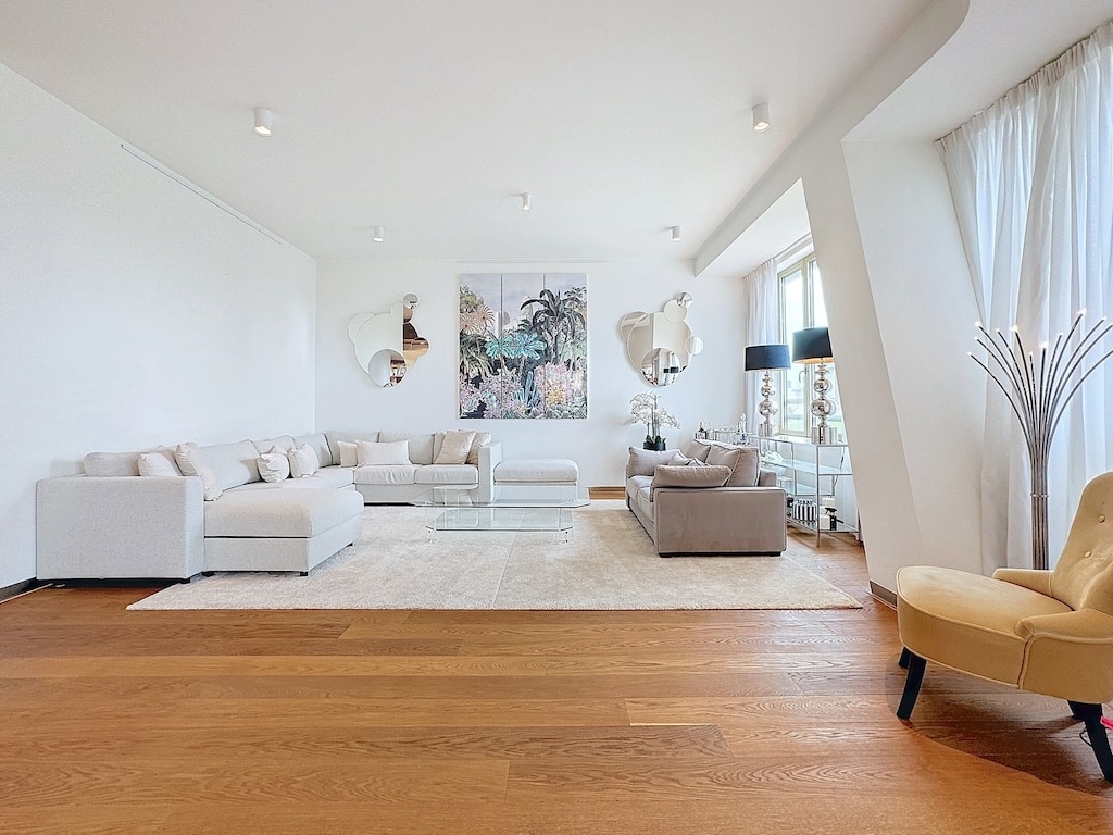 Salon moderne lumineux avec canapé beige, art contemporain, grande fenêtres et décoration épurée.