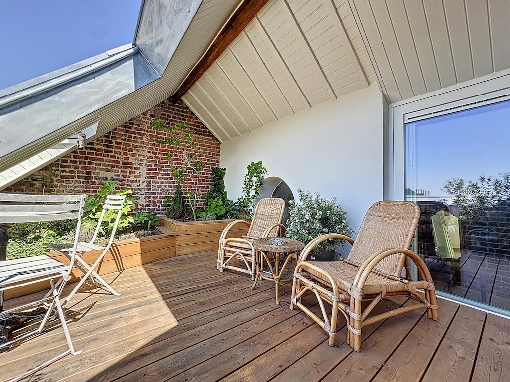 Terrasse cosy avec mobilier en rotin, plantes vertes et ambiance raffinée en style urbain naturel.