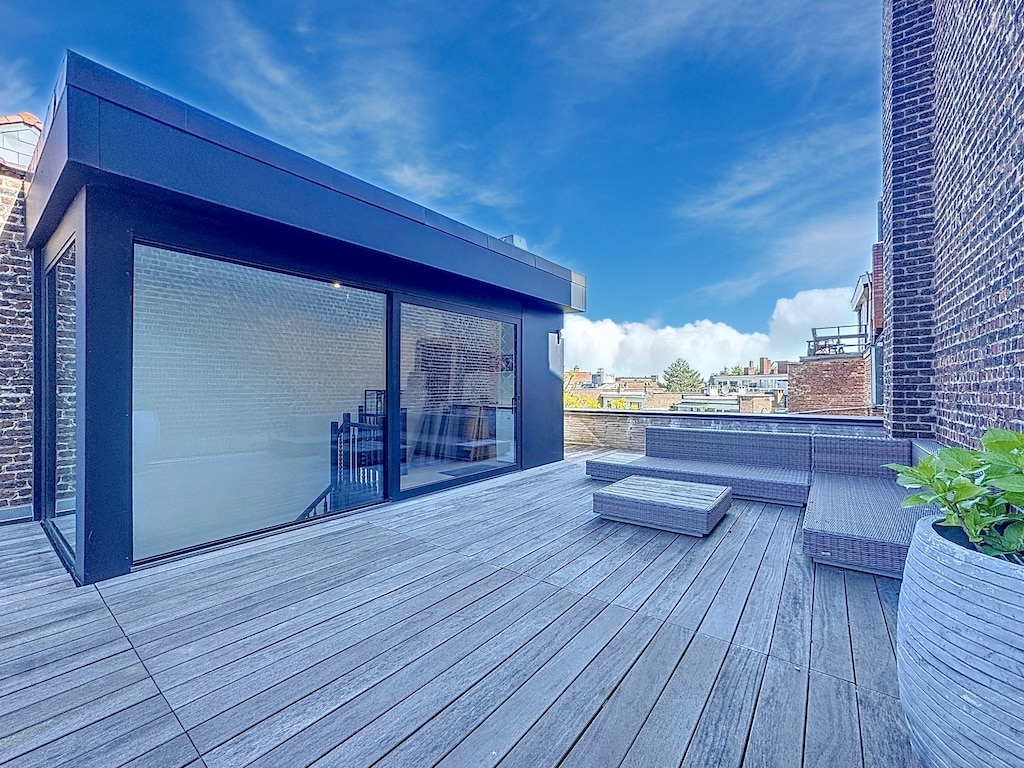 Terrasse rooftop moderne avec mobilier élégant, structure en verre, et vue urbaine contemporaine.