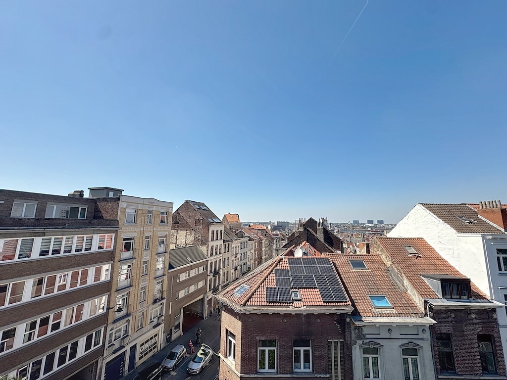 Quartier résidentiel ensoleillé avec bâtiments variés et panneaux solaires sous un ciel bleu clair.