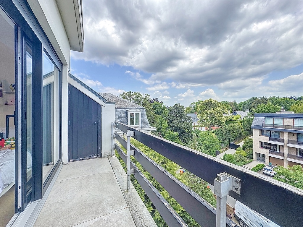Balcon moderne offrant une vue verdoyante, ciel dramatique et ambiance paisible urbaine.