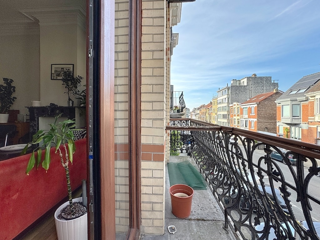 Balcon urbain élégant avec vue, plantes en pot, intérieur cosy et ambiance colorée.