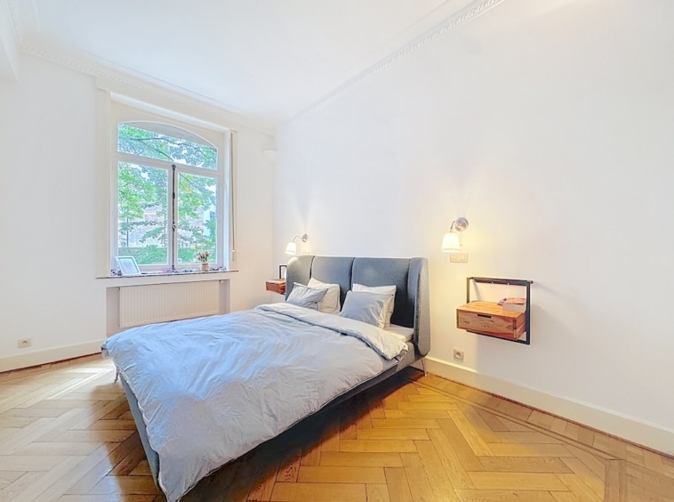 Chambre moderne et apaisante avec lit bleu, lumière naturelle et décoration minimaliste.