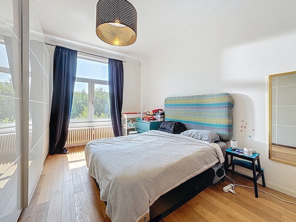 Chambre moderne lumineuse avec lit élégant, grande fenêtre, mobilier miroir et décoration minimaliste.