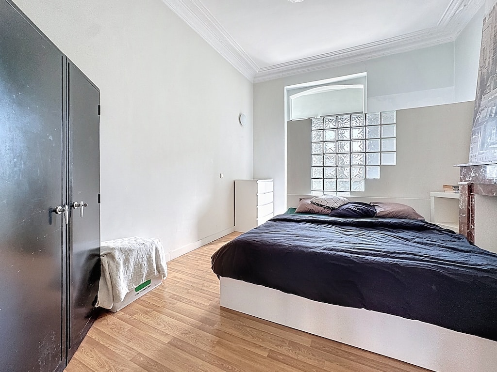 Chambre moderne minimaliste éclairée par la lumière naturelle, avec lit contrasté et mobilier sleek.