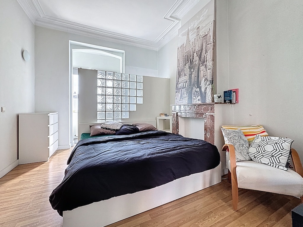 Chambre moderne minimaliste avec lit noir, décoration artistique, cloison en verre et ambiance raffinée.