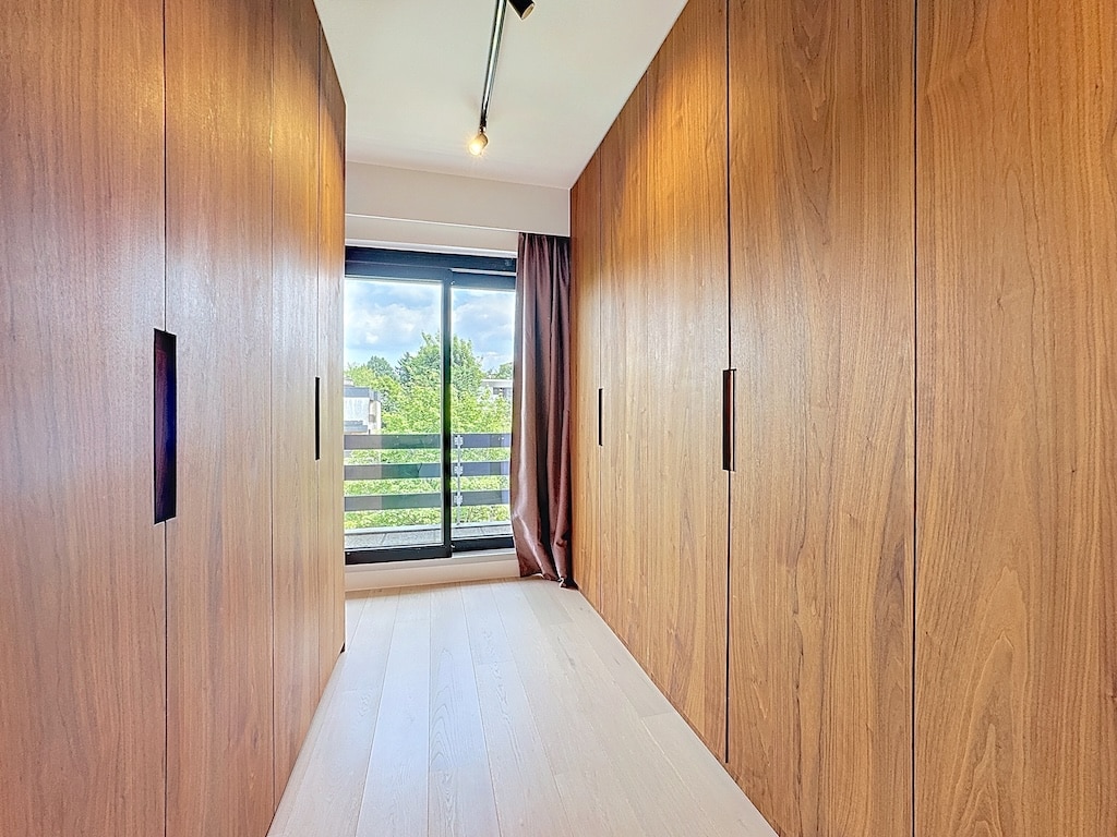 Couloir moderne en bois, lumière naturelle, rangement intégré, ambiance chaleureuse et design épuré.