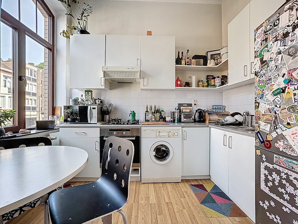 Cuisine lumineuse, moderne, pratique avec mobilier blanc, plantes, appliances, et décoration personnalisée.