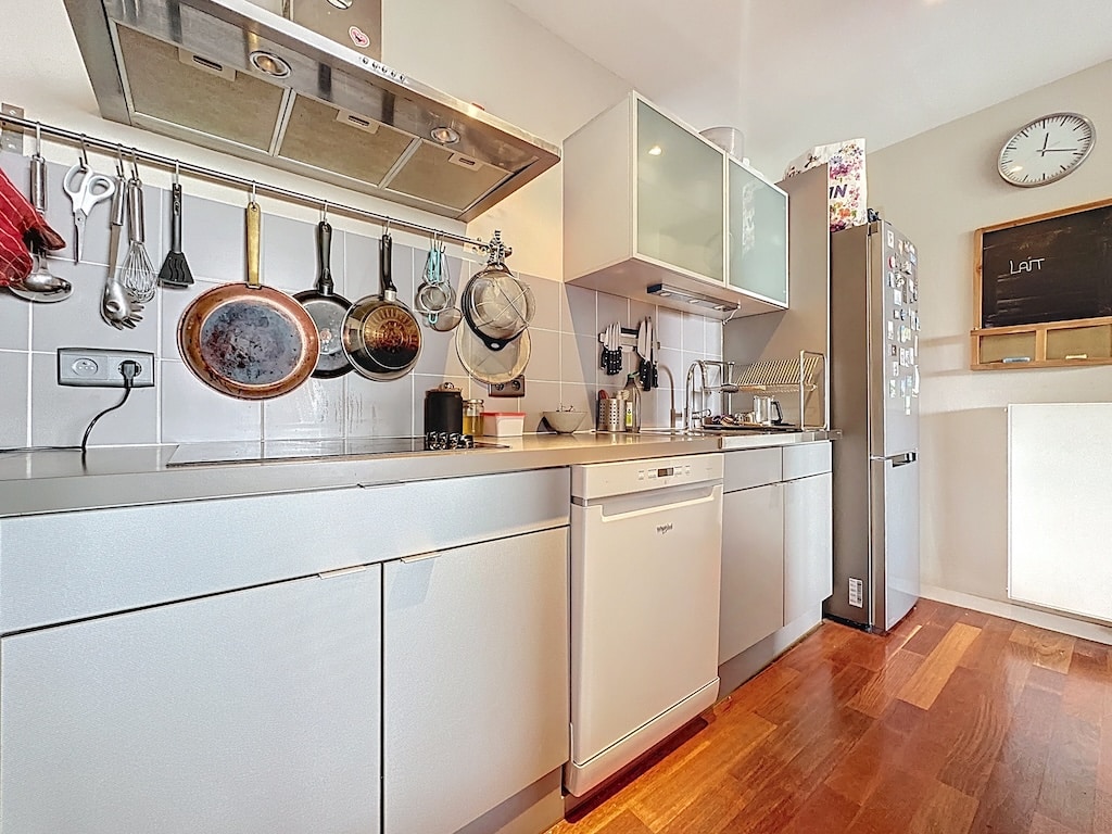 Cuisine moderne épurée avec plan en pierre, rangement pratique, éclairage naturel et touches chaleureuses.