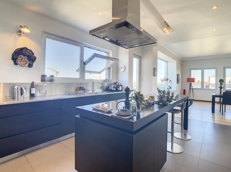 Cuisine moderne lumineuse avec îlot noir, grande baie vitrée et décor minimaliste coloré.