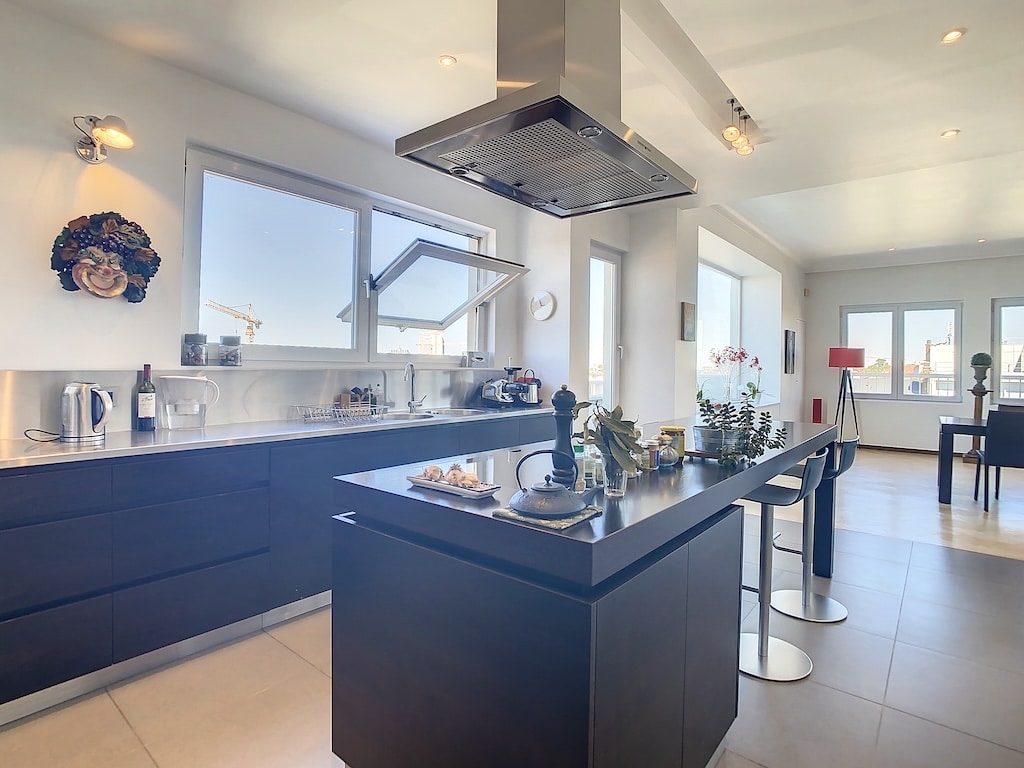 Cuisine moderne lumineuse avec îlot noir, grande baie vitrée et décor minimaliste coloré.