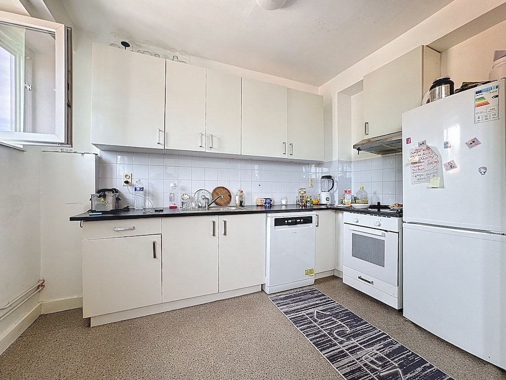 Cuisine moderne minimaliste avec plans foncés, appareils intégrés et éclairage naturel.