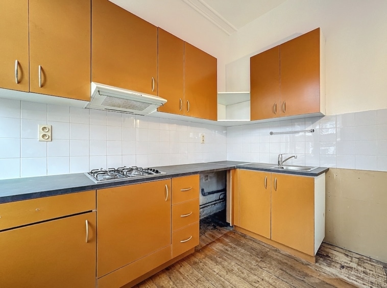 Cuisine chaleureuse avec mobilier en bois, plaque gaz, évier inox et sol en bois naturel.
