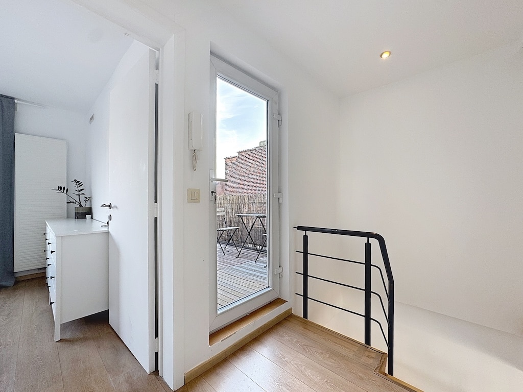 Intérieur moderne avec balcon lumineux, mobilier minimaliste, murs blancs et ambiance urbaine élégante.