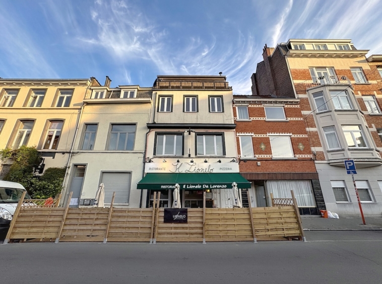 Rue colorée avec café convivial, bâtiments en briques, ambiance chaleureuse sous ciel bleu.