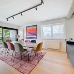 Salle à manger élégante lumineuse avec mobilier coloré, art abstrait, vue extérieure et décoration moderne.