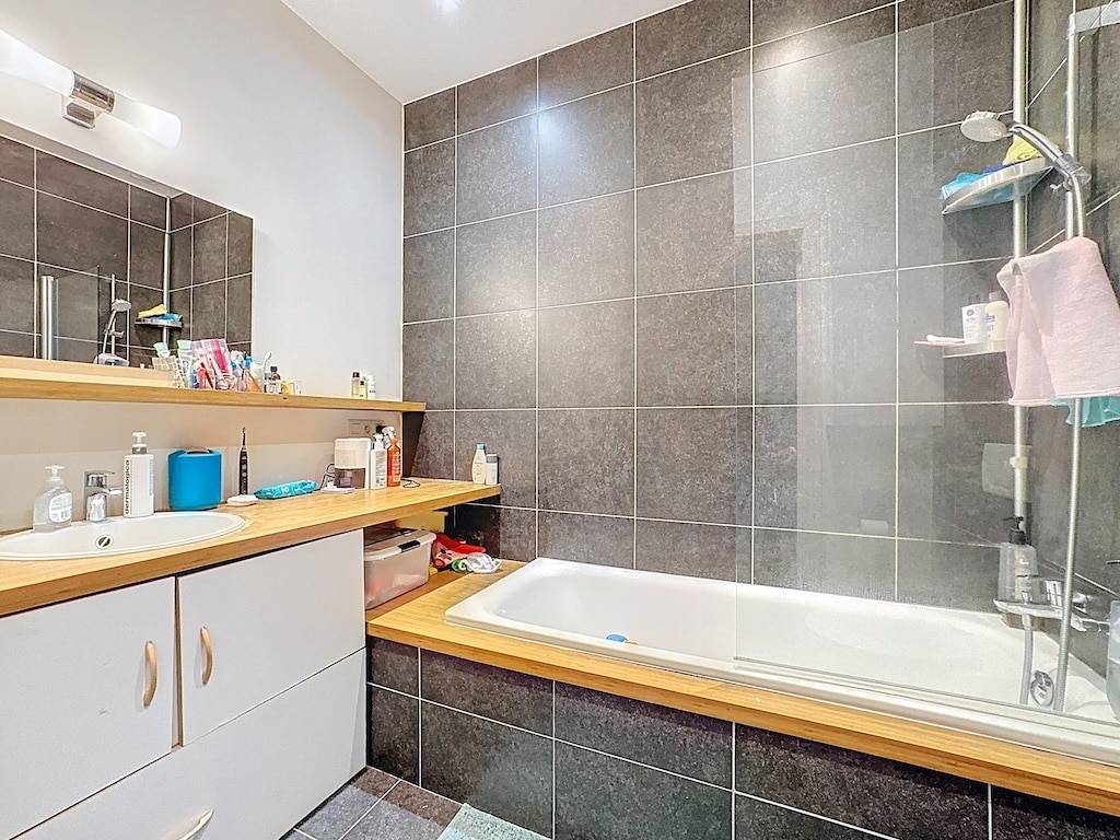 Salle de bain moderne avec baignoire minimaliste, douche en verre et éclairage doux.