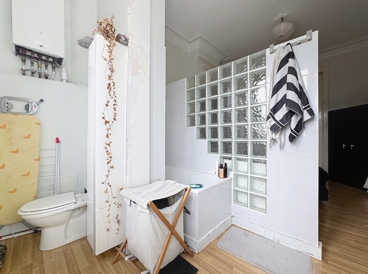 Salle de bain moderne avec baignoire, douche en blocs de verre et décoration minimaliste.
