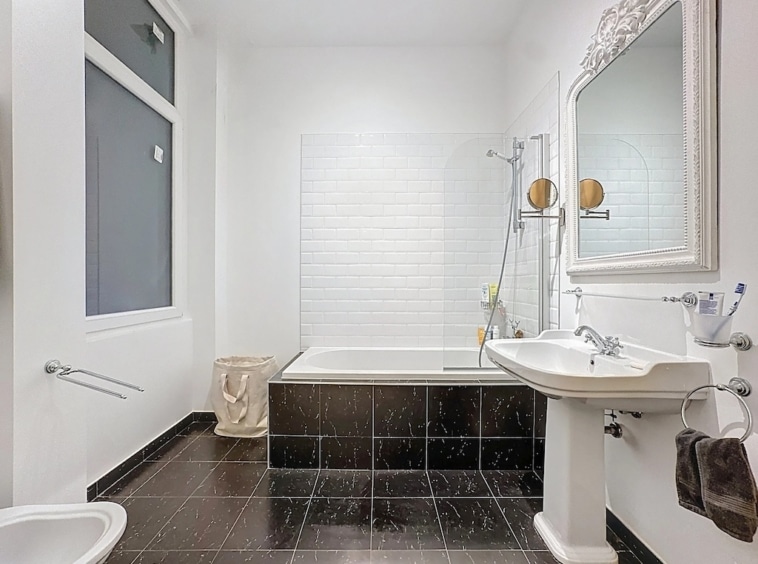 Salle de bain moderne avec douche à litalienne, baignoire et design épuré en blanc et noir.