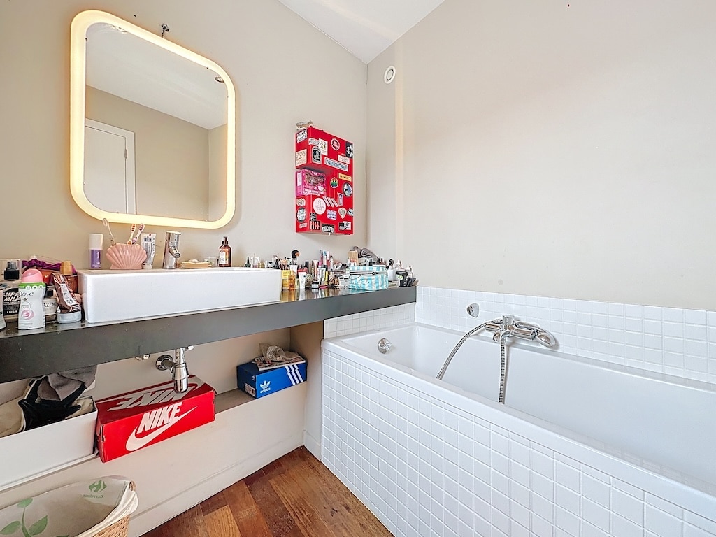 Salle de bain moderne avec plan de travail, baignoire élégante et touches de décoration.