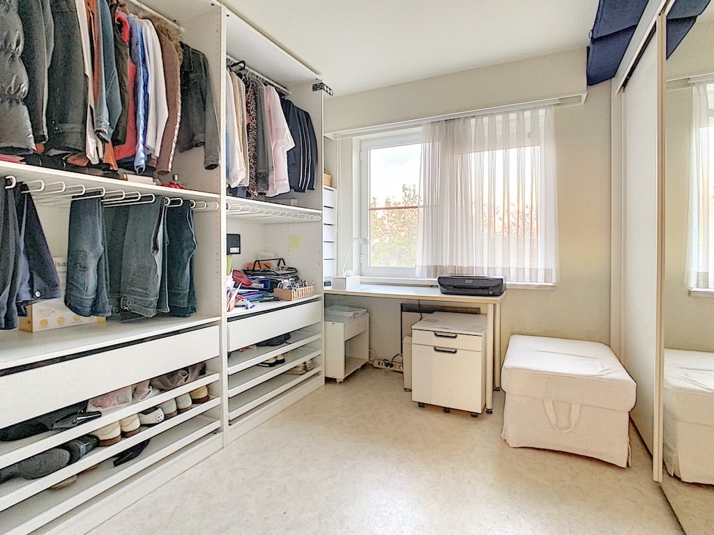 Salle de dressing moderne lumineuse, rangement organisé et espace fonctionnel avec lumière naturelle.