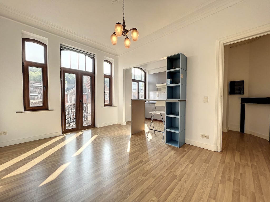 Salon lumineux avec fenêtres en arche, meuble bleu, séparation moderne et vue extérieure.