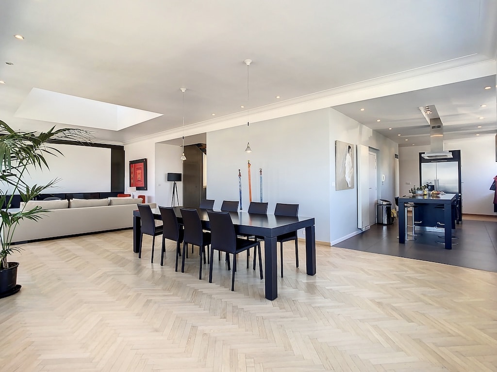 Salon moderne avec cuisine ouverte, mobilier élégant, sol en bois clair, ambiance chaleureuse et sophistiquée.
