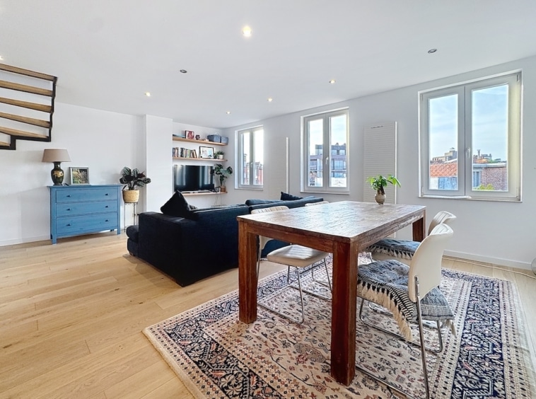 Salon moderne lumineux avec mobilier épuré, lumière naturelle, canapé bleu marine et décoration élégante.
