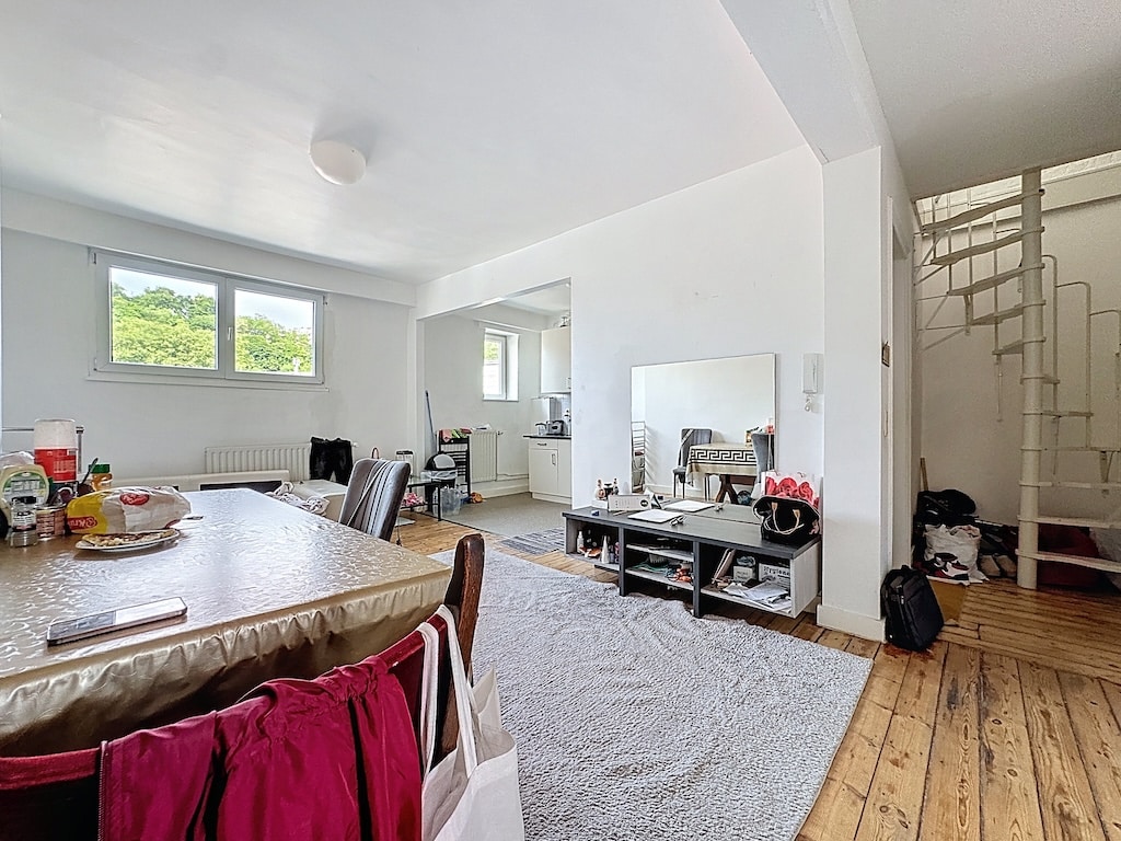 Salon moderne lumineux avec cuisine ouverte, mobilier cosy, escalier hélicoïdal et déco chaleureuse.