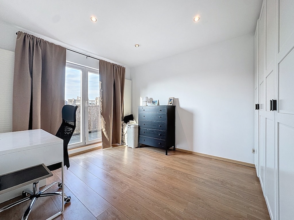 Salon moderne lumineux avec bureau, grande baie vitrée, mobilier épuré, espace de travail élégant.