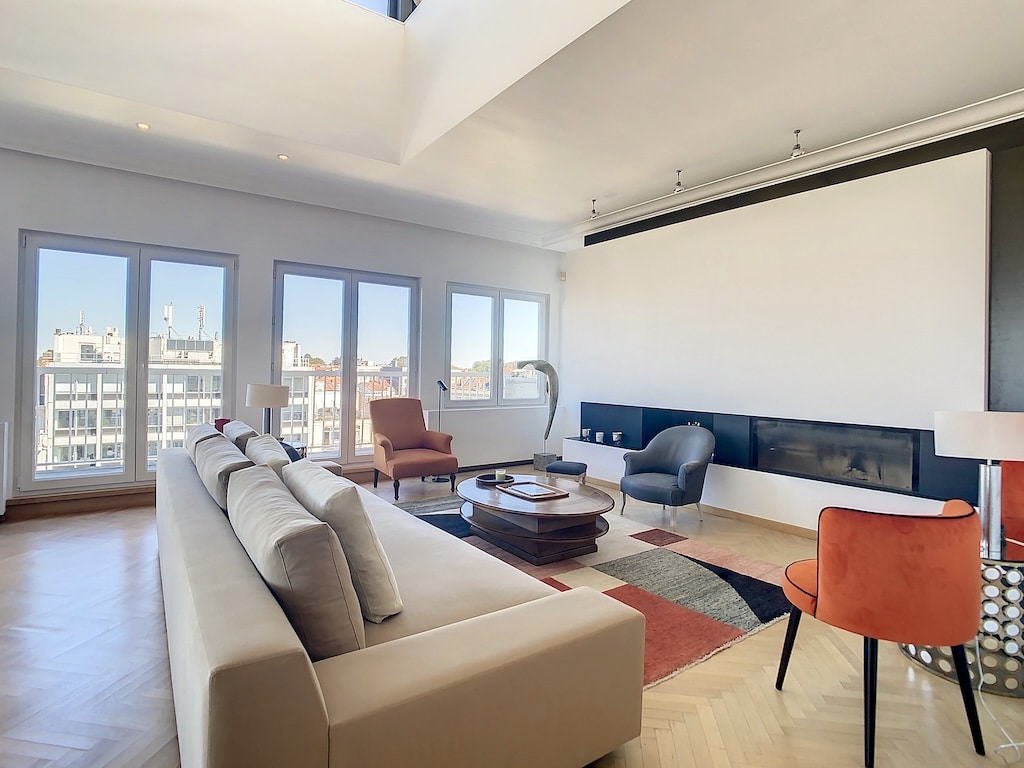 Salon moderne lumineux avec canapé beige, chaise orange, cheminée noire et décoration élégante.