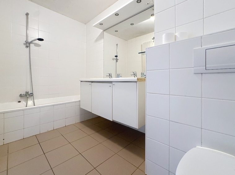 Salle de bains moderne avec double vasque, baignoire et douche, design épuré et lumineux.