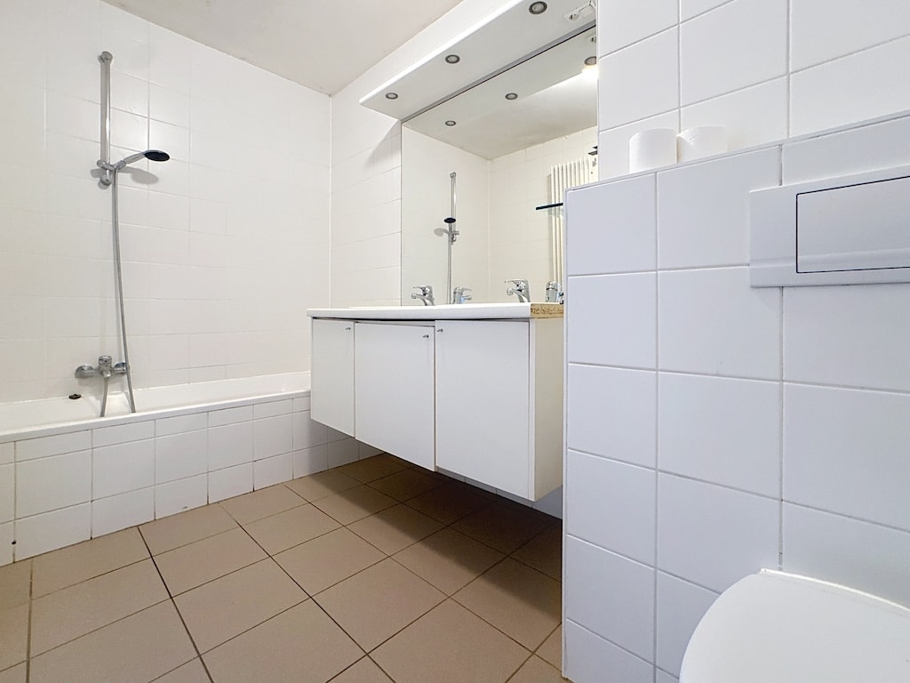 Salle de bains moderne avec double vasque, baignoire et douche, design épuré et lumineux.