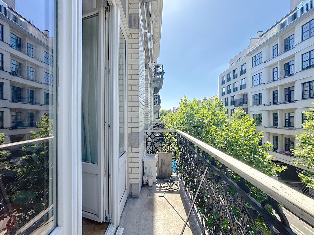 Balcon ensoleillé avec vue moderne, ferronnerie élégante et nature verdoyante environnante.