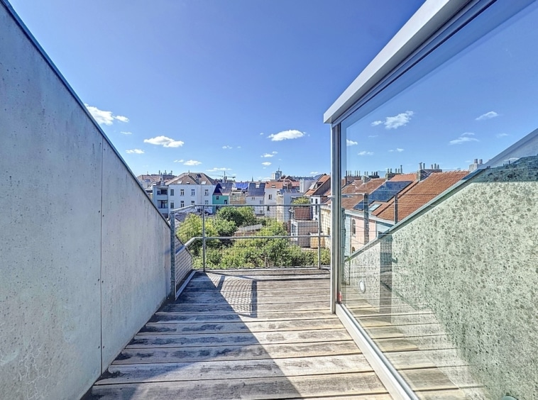 Balcon moderne en bois et verre offrant une vue panoramique sur la ville et la nature.