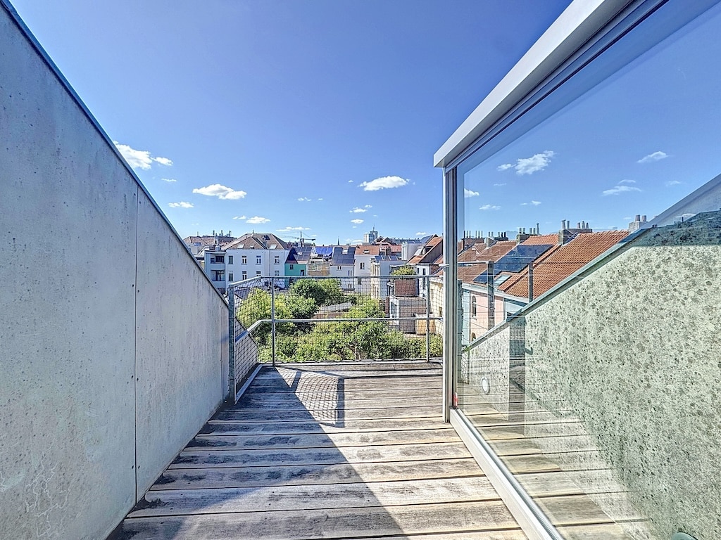 Balcon moderne en bois et verre offrant une vue panoramique sur la ville et la nature.