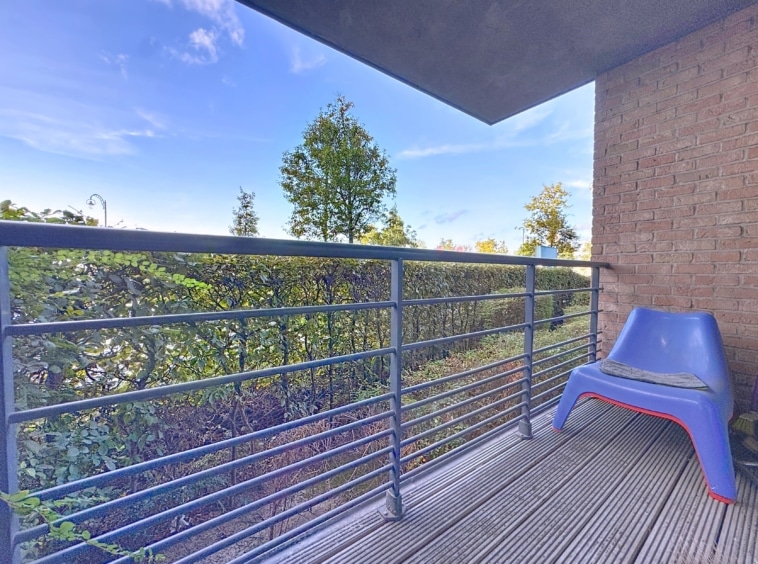 Balcon minimaliste avec fauteuil bleu, vue verdoyante, ambiance paisible et design contemporain.