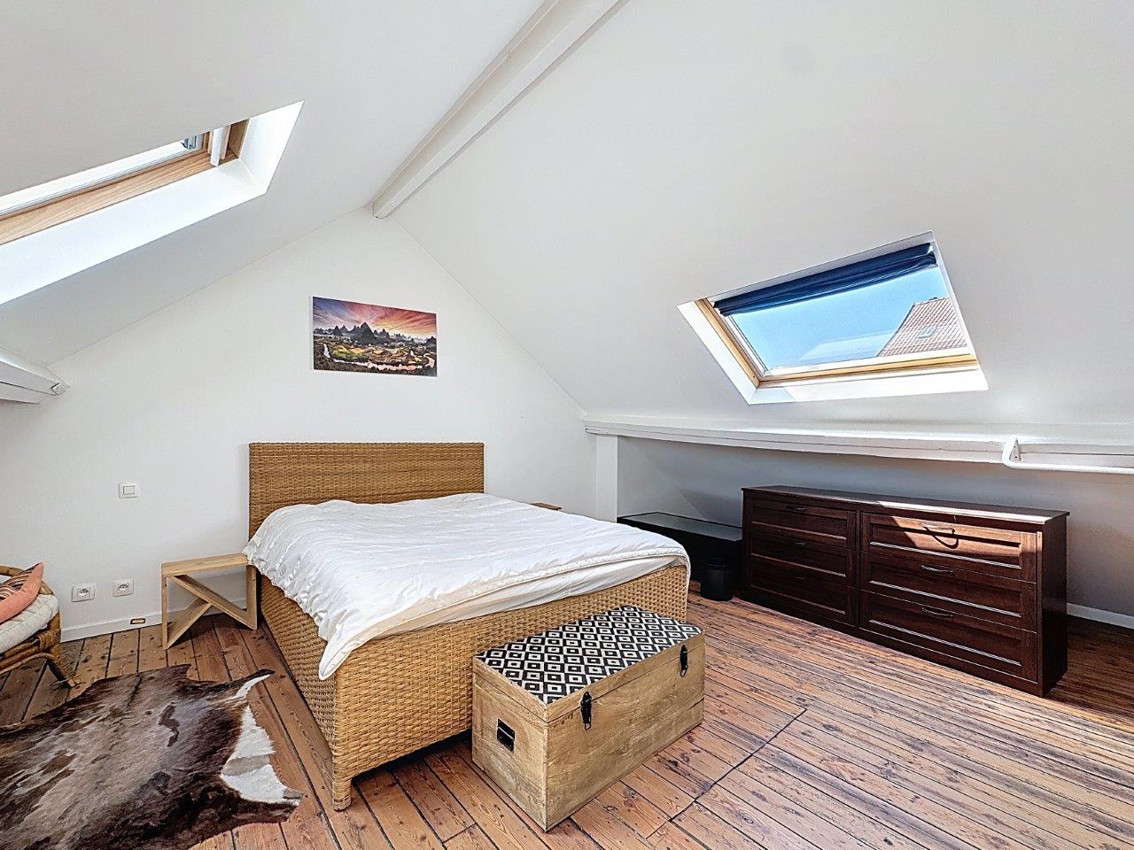 Chambre attic cosy avec puits de lumière, meubles en bois rustique et décoration moderne.