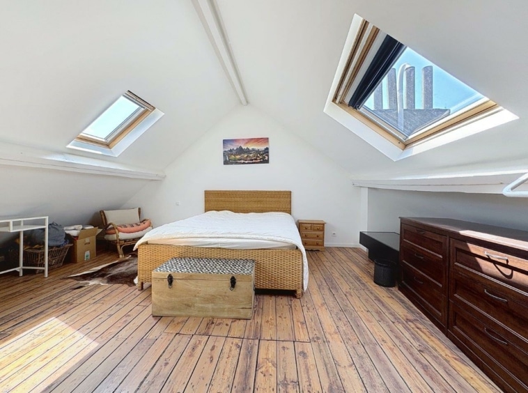 Chambre attic lumineuse et cozy avec mobilier en bois, décoration simple et ambiance paisible.
