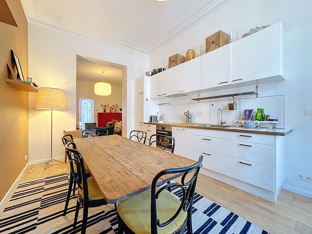 Cuisine élégante et chaleureuse avec mobilier en bois, rangements blancs et ambiance conviviale.