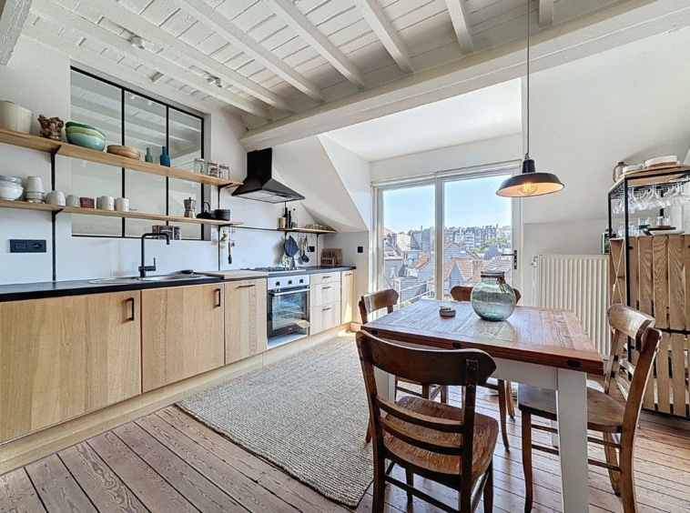 Cuisine moderne chaleureuse avec meubles en bois, plan blanc et espace repas lumineux et convivial.